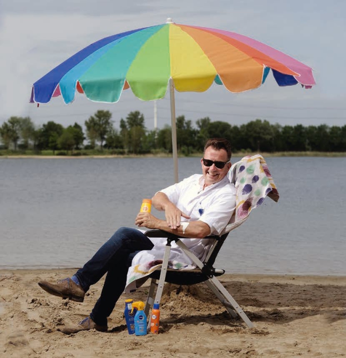 Dermatolog Rob Veenhuis aan de recreatieplas Stroombroek met parasol en zonnebrand.
